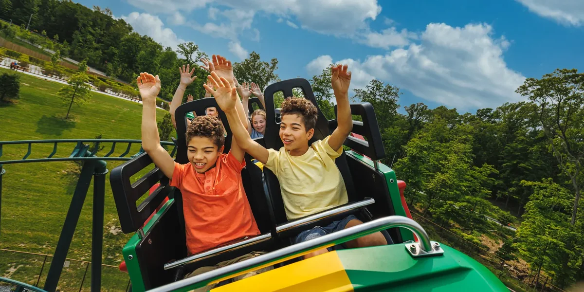 Children smiling on a LEGOLAND New York coaster used for season pass promotion